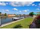 Waterfront backyard with green grass, dock, a shade sail, and lush pink flowers on a beautiful day at 3912 Doral Dr, Tampa, FL 33634