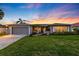 Well-maintained home featuring a lush lawn, mature landscaping, and a two-car garage against a sunset backdrop at 3912 Doral Dr, Tampa, FL 33634