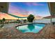Backyard pool with brick trim, a wooden deck, shade sail, and lush tropical landscaping at dusk at 3912 Doral Dr, Tampa, FL 33634