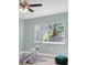 Bedroom features laminate floors, a ceiling fan, a bright window, and light blue walls at 4055 Floramar Ter, New Port Richey, FL 34652