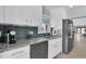 Kitchen with white cabinets, gray appliances, granite countertops, and tiled backsplash at 4055 Floramar Ter, New Port Richey, FL 34652