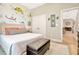 Well-lit bedroom featuring a queen-size bed, artistic wall, a leather storage bench, and views through an open doorway at 4093 Epic Cv, Land O Lakes, FL 34638