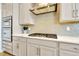 Gourmet kitchen with gas cooktop, modern backsplash, and stainless steel appliances built into light gray cabinets at 4093 Epic Cv, Land O Lakes, FL 34638