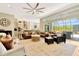 Spacious living room with a large leather sofa, ceiling fan, and view of the outdoor pool area at 4093 Epic Cv, Land O Lakes, FL 34638