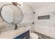 Modern bathroom with marbled walls, mosaic accents, a round mirror, and a black granite vanity at 4228 Tarpon Se Dr, St Petersburg, FL 33705