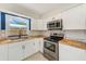 Charming kitchen with white cabinets, butcher block countertops, stainless steel oven, range hood, and backsplash at 4228 Tarpon Se Dr, St Petersburg, FL 33705