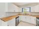 Bright kitchen features white cabinets, butcher block countertops, stainless steel dishwasher, and backsplash at 4228 Tarpon Se Dr, St Petersburg, FL 33705