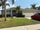 Charming single-story home featuring a well-manicured lawn, attached garage, and inviting blue double-door entry at 4512 River Overlook Dr, Valrico, FL 33596