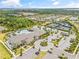 Aerial view of the community clubhouse with a swimming pool, parking, and tennis courts amidst lush landscaping at 4914 Sienna Isles Ave, Wimauma, FL 33598