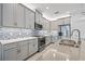 Modern kitchen featuring gray cabinets, stainless steel appliances, mosaic backsplash and stone countertops at 4914 Sienna Isles Ave, Wimauma, FL 33598