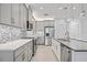 Bright, open kitchen with stainless steel appliances, gray cabinets, a kitchen island, and pendant lights at 4914 Sienna Isles Ave, Wimauma, FL 33598