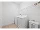 Functional laundry room with washer, dryer, storage shelf, and a tile floor at 4914 Sienna Isles Ave, Wimauma, FL 33598