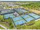 Aerial view showcasing multiple tennis courts with lush landscaping around the court with surrounding green spaces at 4914 Sienna Isles Ave, Wimauma, FL 33598