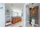 Bright bathroom with double sinks, warm wood cabinetry, and a separate water closet for added privacy at 5040 Inshore Landing Dr, Apollo Beach, FL 33572