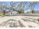 Long concrete driveway leading to a detached garage and additional buildings, surrounded by mature trees and a white fence at 5744 150Th N Ave, Clearwater, FL 33760