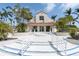 Inviting clubhouse entrance featuring a red tile roof, lush landscaping, and pristine white railings and stairs at 6100 Bahia Del Mar Cir # 105, St Petersburg, FL 33715