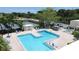 Aerial view of the community pool and whirlpool with lounge chairs and tennis courts in the background at 6190 80Th N St # 102, St Petersburg, FL 33709
