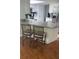 Open kitchen boasts granite countertops, wooden bar stools, stainless steel appliances, and wood floors at 7524 Oakshire Dr, Port Richey, FL 34668