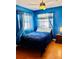 Cozy bedroom featuring blue bedding, wood floors, and natural light from the curtained windows at 821 Karen St, Palm Harbor, FL 34684