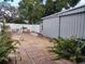 A brick-laid backyard with a storage unit and white fence surrounding the property at 8503 N Willow Ave, Tampa, FL 33604