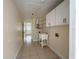 Bright laundry room with cabinetry, tiled floors, and utility sink at 8503 N Willow Ave, Tampa, FL 33604