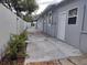 Narrow side yard with concrete and brick pathway, white fence, and gray siding at 8503 N Willow Ave, Tampa, FL 33604