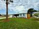 Inviting single-story home with a fresh lawn, new landscaping, and a mature palm tree at 9005 Rainbow Ln, Port Richey, FL 34668