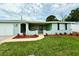 Charming single-story home featuring a manicured lawn and fresh landscaping around the entrance at 9005 Rainbow Ln, Port Richey, FL 34668