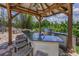 The outdoor kitchen features granite countertops, stainless steel appliances, barstool seating and outdoor views at 9208 Brindlewood Dr, Odessa, FL 33556