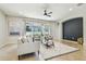 A spacious living room with large windows, ceiling fan and a black accent wall at 9317 Bella Vita Cir, Land O Lakes, FL 34637