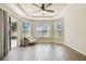 Bright main bedroom with a tray ceiling, wood-look flooring, and a sliding glass door to the patio at 9317 Bella Vita Cir, Land O Lakes, FL 34637