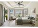Staged main bedroom features tray ceilings, a seating area, and a sliding glass door to the patio at 9317 Bella Vita Cir, Land O Lakes, FL 34637