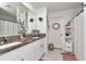 Clean bathroom featuring double sinks, granite countertops, decorative details, and shower with curtain at 9734 Branching Ship Trce, Wesley Chapel, FL 33545