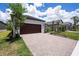 A well-maintained home showing a brown garage door with a brick driveway surrounded by green lawns at 10098 Banyan Breeze Blvd, Land O Lakes, FL 34638