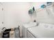 Practical laundry room with white washer and dryer, shelving, and a laundry basket organizer at 10098 Banyan Breeze Blvd, Land O Lakes, FL 34638