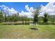 Lush green landscape and tranquil pond, enhanced by mature trees and clear blue sky at 10098 Banyan Breeze Blvd, Land O Lakes, FL 34638