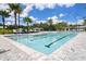 Community pool with several steps leading down, lane markers, and lounge chairs under a sunny sky at 10098 Banyan Breeze Blvd, Land O Lakes, FL 34638