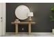An entryway exhibits a simple table with a lamp and a round mirror against a gray accent wall at 10225 Trumpet Honeysuckle Way, San Antonio, FL 33576