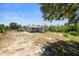 Back exterior view of the home with light grey paint, metal roof, and large backyard at 11009 Spivey Rd # 1, Gibsonton, FL 33534