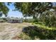 Exterior showcasing the home's setting amidst nature with trees and a lush lawn at 11009 Spivey Rd # 1, Gibsonton, FL 33534