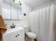 Well-lit bathroom features a vanity, toilet, and shower with a neutral-colored shower curtain at 1221 E Hamilton Ave, Tampa, FL 33604