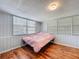 Sun-drenched bedroom boasts three windows, wood paneling, and sleek hardwood floors with baseboard trim at 1221 E Hamilton Ave, Tampa, FL 33604