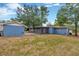 Image shows a large backyard, including a blue shed, screen porch, and the back of a blue single story home at 1304 N Ferrell St, Plant City, FL 33563