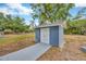 Shot of a small blue square shed with white double doors, situated at the end of a long concrete walkway at 1304 N Ferrell St, Plant City, FL 33563