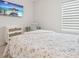 Comfortable bedroom featuring a floral quilt bed, desk and chair, and a TV at 13098 Wellspring Dr, Lithia, FL 33547