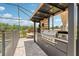 Outdoor kitchen with stainless steel grill, pizza oven, and mini fridge with a shaded dining area at 13098 Wellspring Dr, Lithia, FL 33547