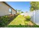 Spacious backyard with lush green lawn, garden plants, and a white privacy fence at 13201 Wellington Hills Dr, Riverview, FL 33579