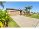 A single-story home has neutral siding, a two-car garage and small palm trees in the front yard at 13201 Wellington Hills Dr, Riverview, FL 33579