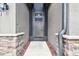 A screened front door is centered between stone columns beneath a light fixture at 13201 Wellington Hills Dr, Riverview, FL 33579
