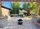 Backyard brick patio with fire pit, dining under a tiki umbrella, complemented by lush bamboo and serene landscape at 13201 Wellington Hills Dr, Riverview, FL 33579